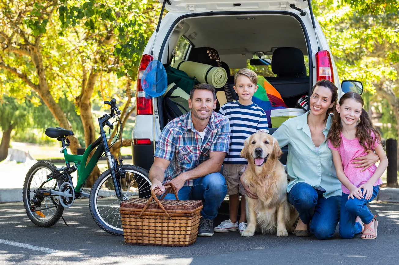 American Family preparing to go camping with golden retriever in front. 