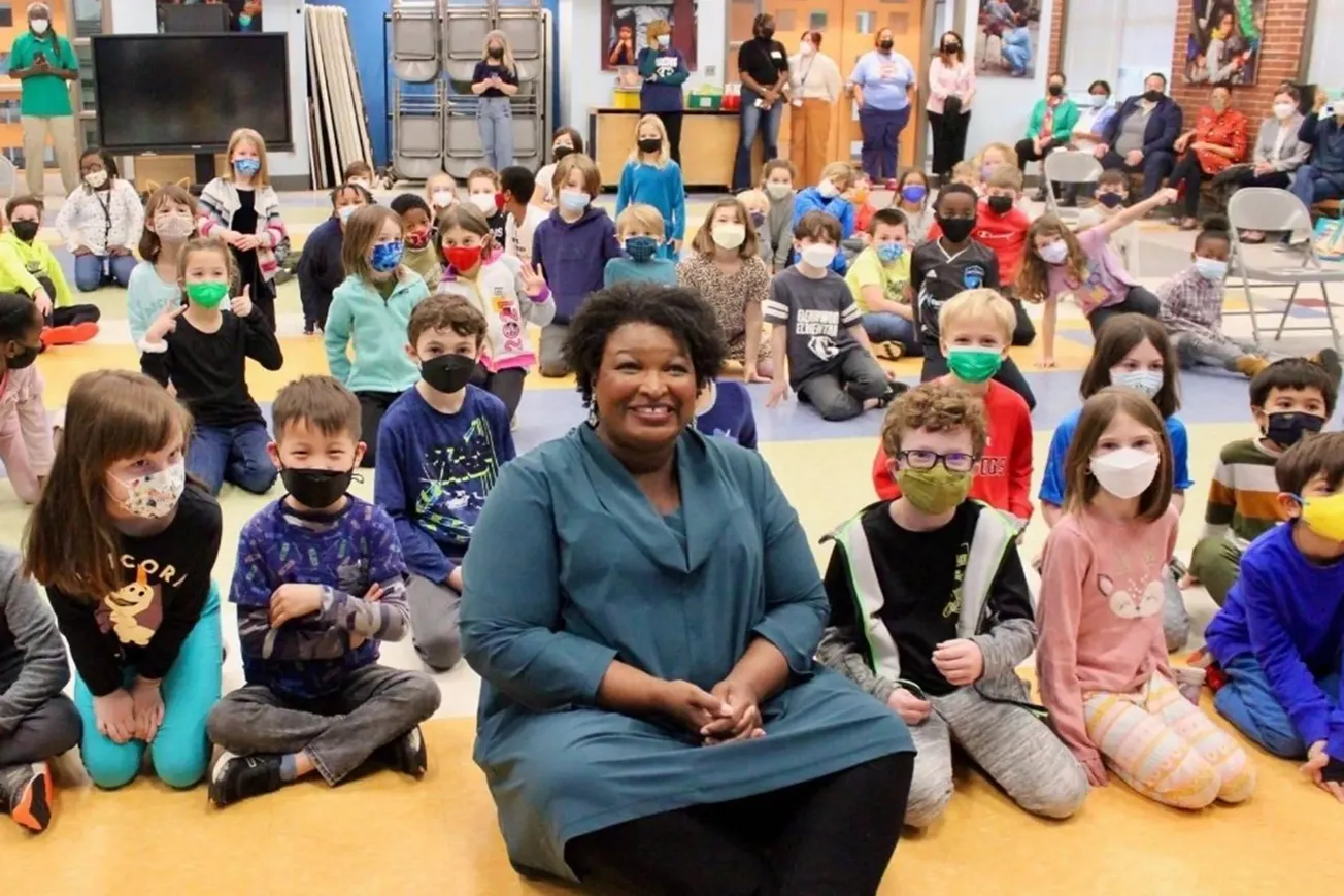 Stacey Abrams in a classroom not wearing a mask surrounded by children who are wearing masks
