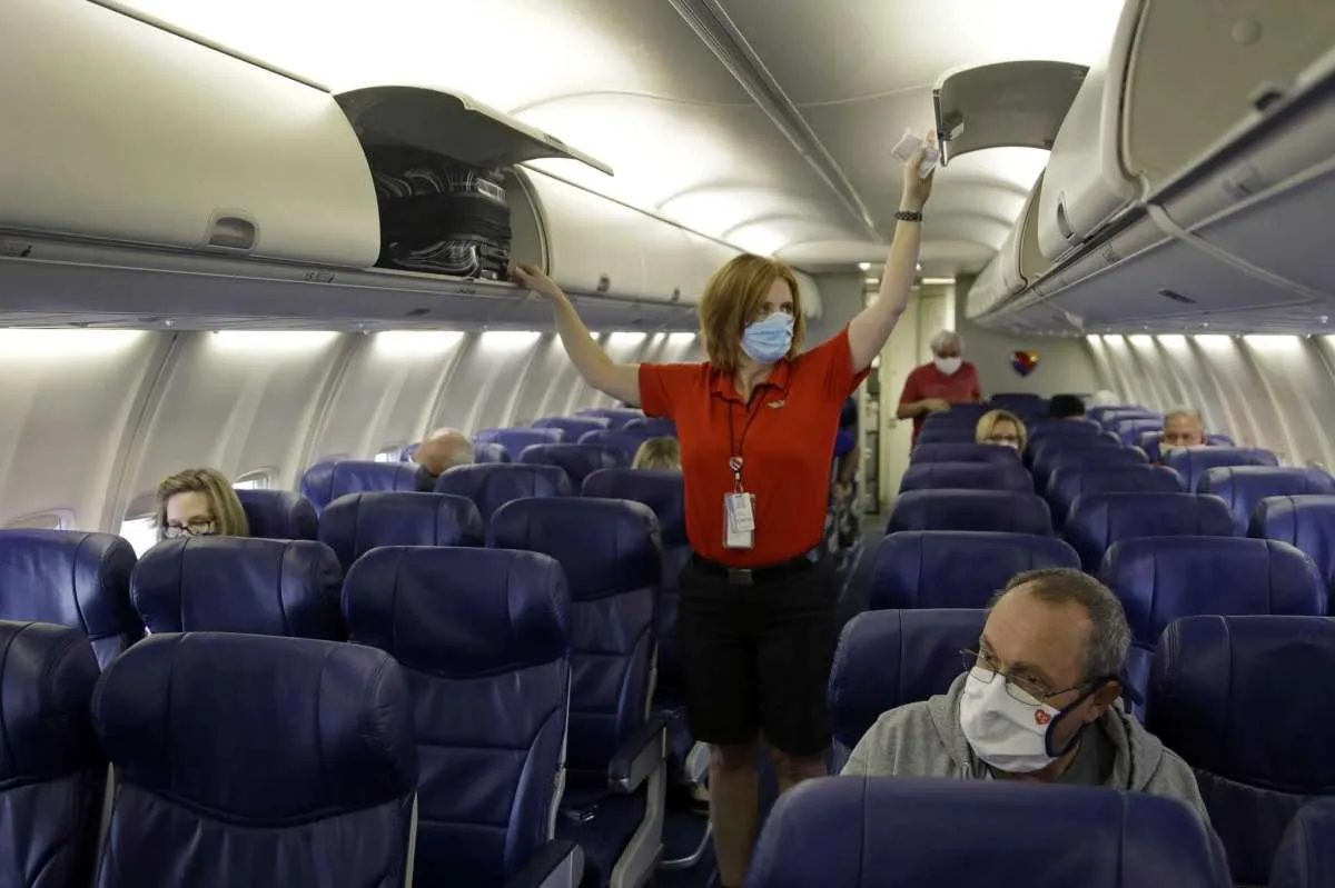 Flight Attendant putting overhead luggage in bins