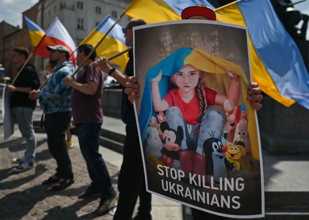 Ukrainian protestors holding "stop killing Ukrainians sign"