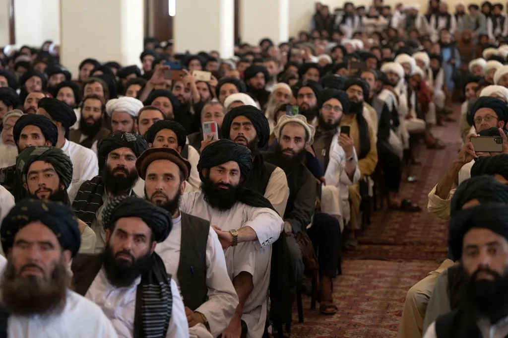 Taliban members listen to Afghanistan's Prime Minister Mohammad Hassan Akhund